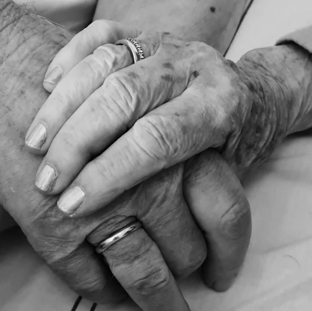 Handen die elkaar lief hebben in elkaar gevouwen. Afscheid bij Alzheimer is een lang proces.